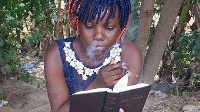 Nigerian girl smoking and reading Bible
