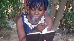 Nigerian girl smoking and reading Bible